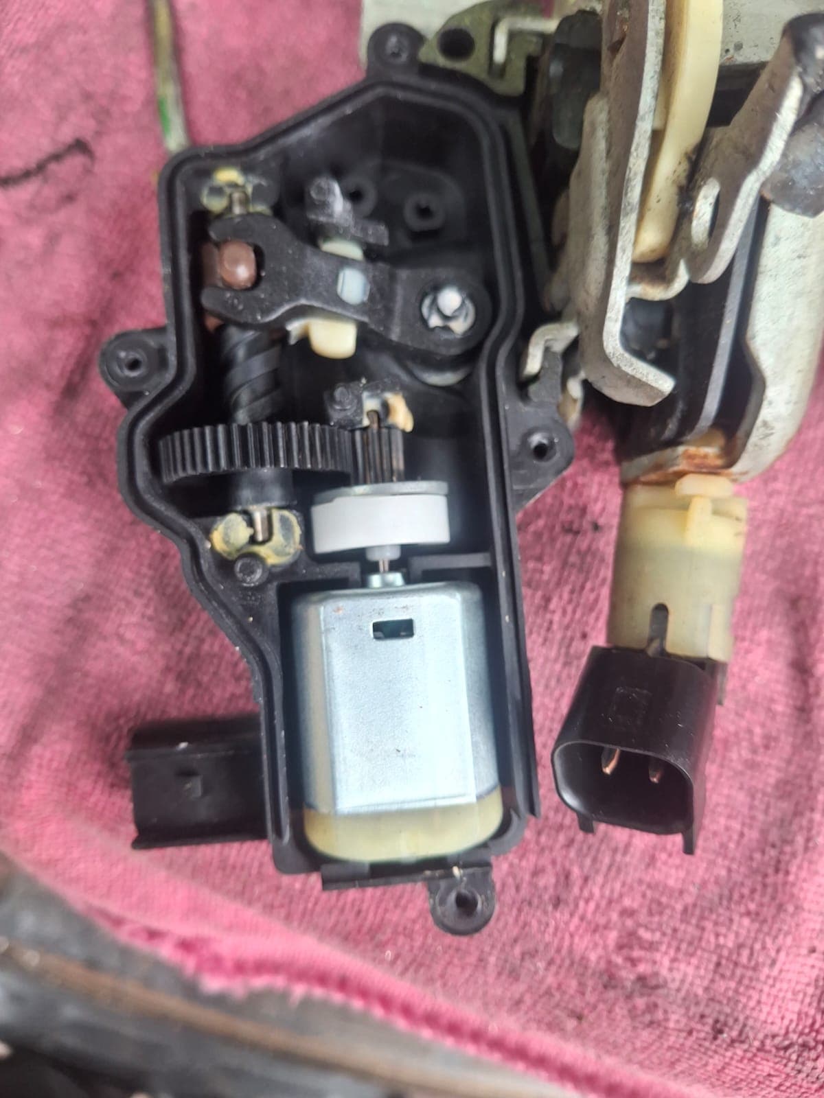 Actuador eléctrico de cerradura de puerta de vehículo desarmado durante reparación por Cerrajería V. Meza
