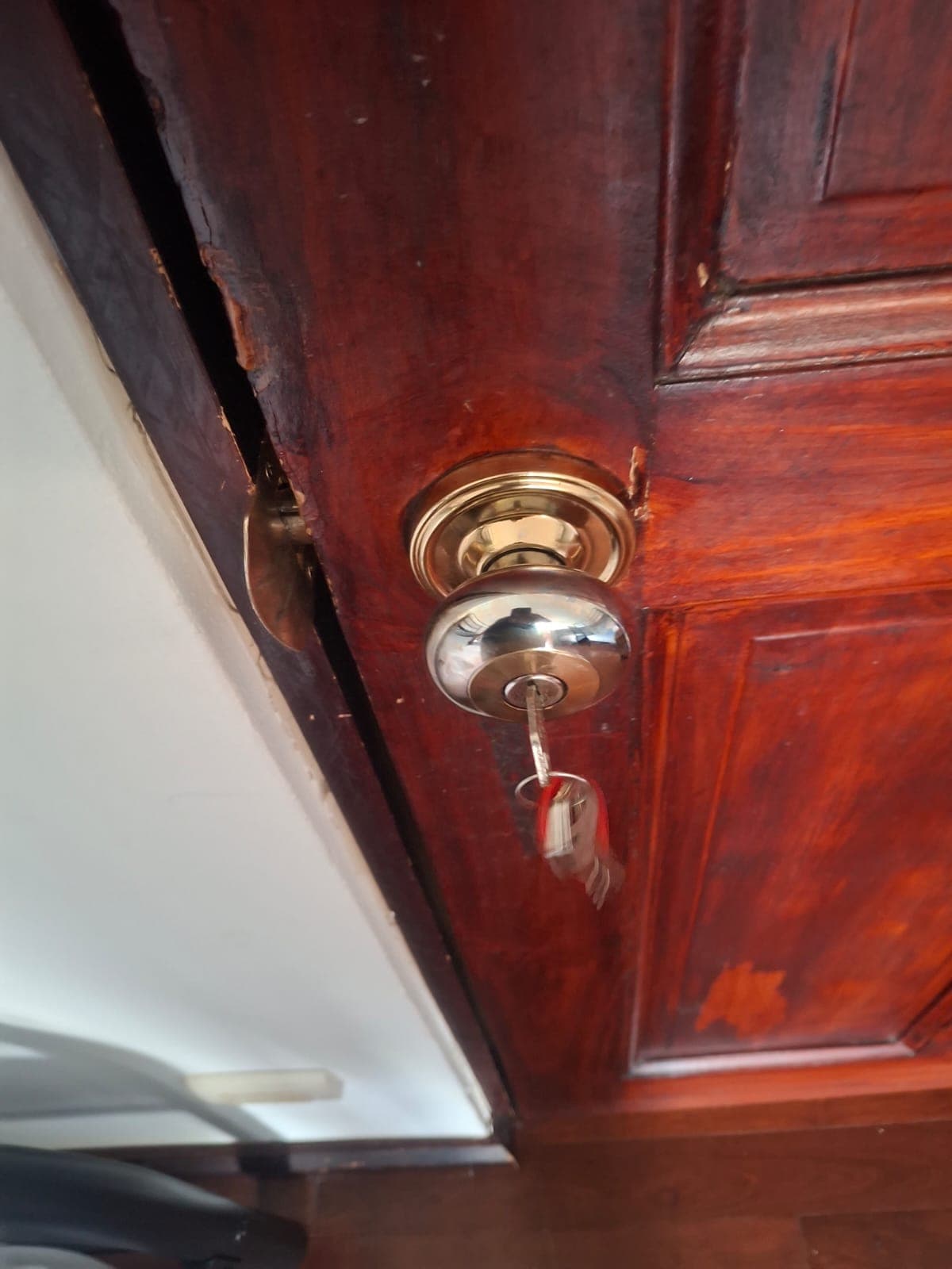 Cerradura de pomo cromada instalada en puerta de madera residencial con llave puesta, trabajo de Cerrajería V. Meza en Costa Rica